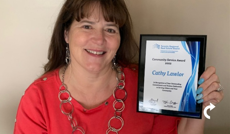Cathy Lawlor smiling and holding her 2022 Community Service Award