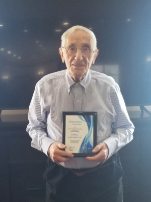 Daniel Gargarella smiling and holding his over 60 years of TRREB membership award in 2022.
