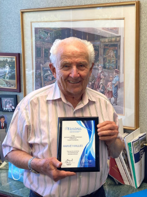 Harvey Kalles smiling and holding his over 60 years of TRREB membership award in 2022.