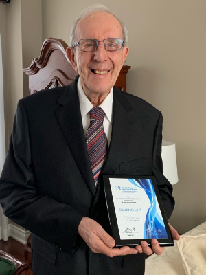Silvano Liut smiling and holding his over 60 years of TRREB membership award in 2022.